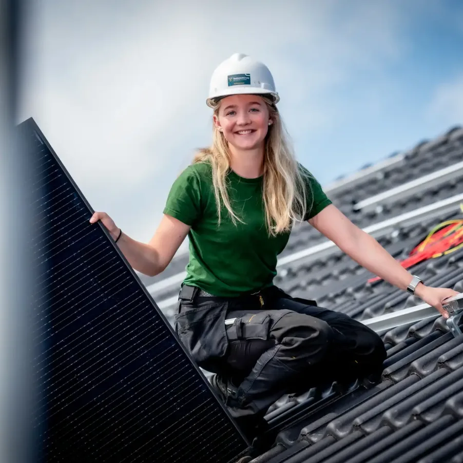 Jonge vrouw legt energiebesparende zonnepanelen op een dak en werkt zo aan duurzaamheid.