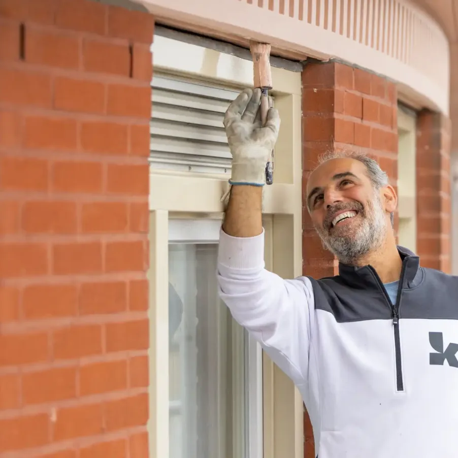 Een schilder van één van de NOK.5 regiobedrijven schildert een raamkozijn.